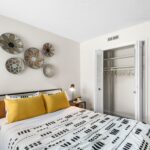 3-Bedroom Apartments in Winter Park, FL - The Taylor - Bedroom with Black Bed Frame, White Walls, Wall Art, Yellow Pillow